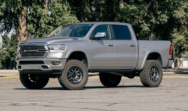 ReadyLIFT MAX3.3 Suspension System installed on a Ram 1500: gray Ram 1500 crew cab lifted on gray wheels and mud tires in a paved lot