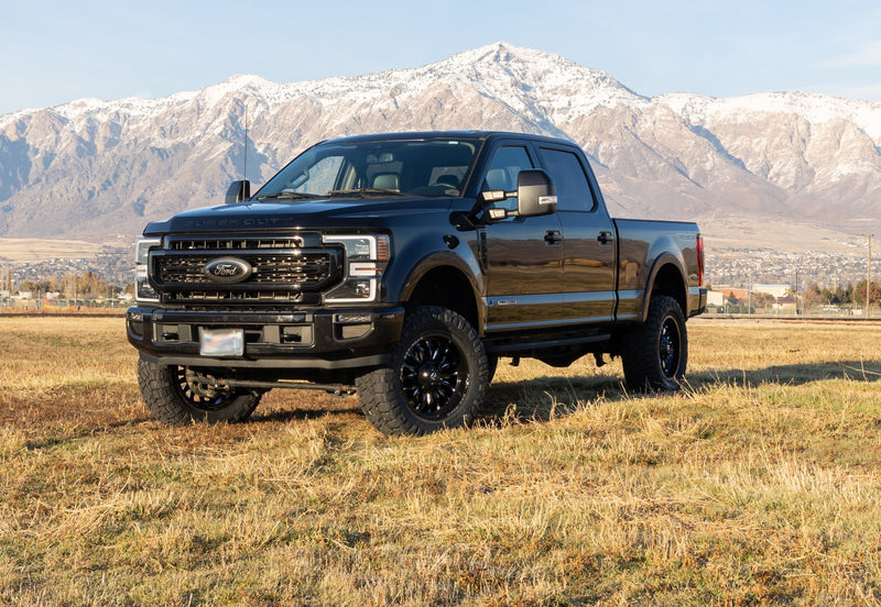 ReadyLIFT SST Lift Kit installed on a Ford F-250 Super Duty: A black lifted Ford Super Duty Crew Cab parked in a field with snowy mountains behind