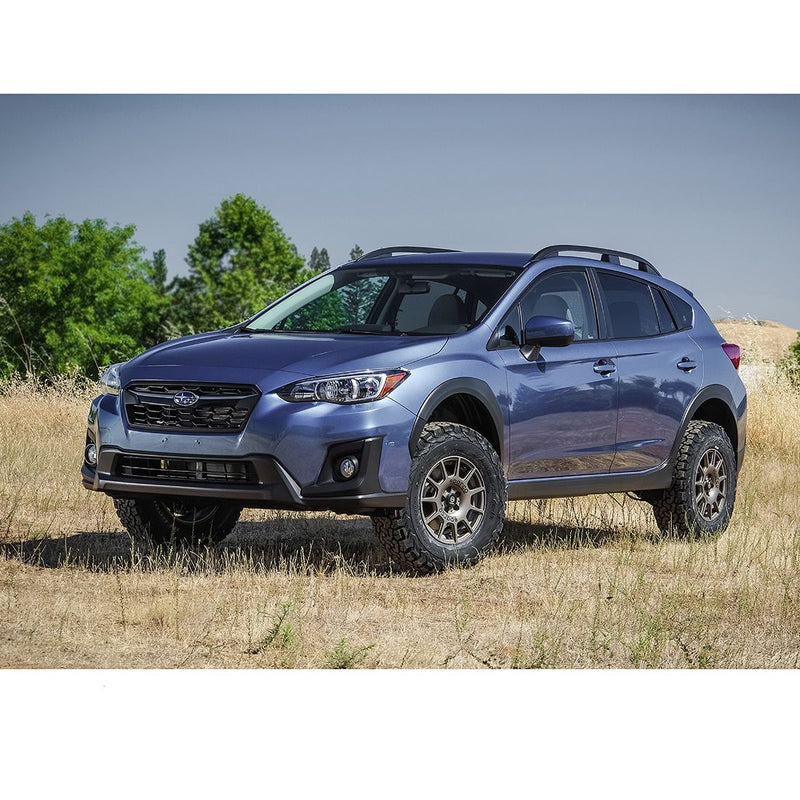 ReadyLIFT SST Lift Kit installed on a Subaru Crosstrek: A blue lifted Subaru Crosstrek parked in a dry grass field with trees behind