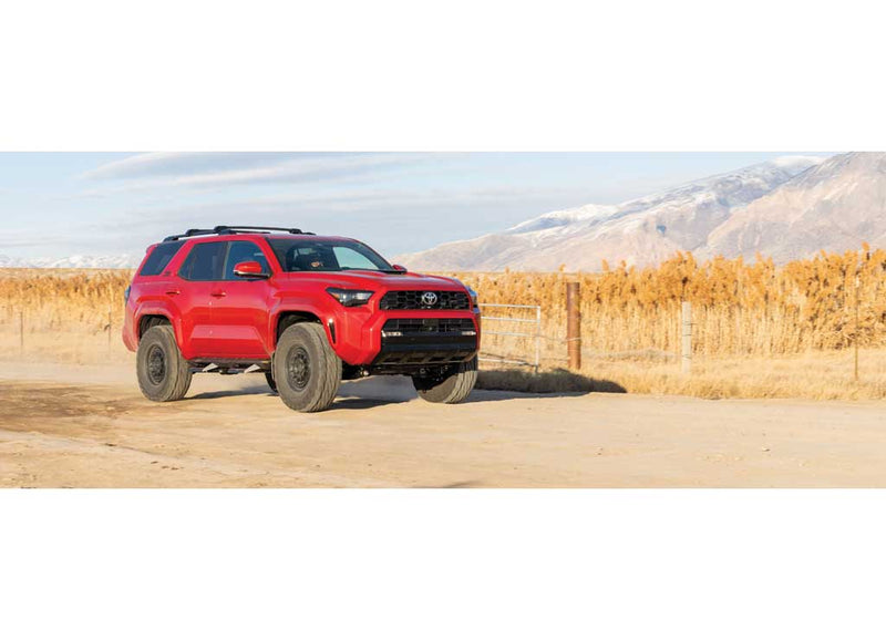 ReadyLIFT SST Lift Kit installed on a Toyota 4Runner: A red lifted Toyota 4Runner on a dirt road with dry reeds and mountains behind