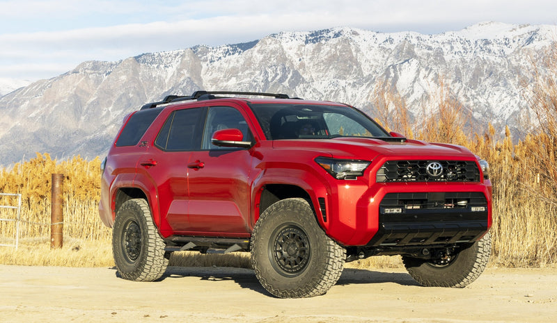 ReadyLIFT SST Lift Kit installed on a Toyota 4Runner: A red lifted Toyota 4Runner parked on dirt with snowy mountains behind