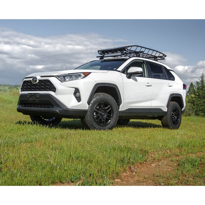 ReadyLIFT SST Lift Kit installed on a Toyota RAV4: A white lifted Toyota RAV4 with a roof basket parked on green grass