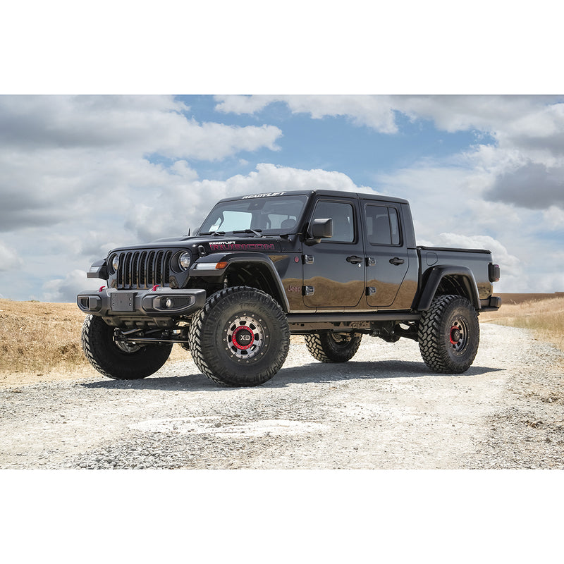 ReadyLIFT Terrain Flex 4-Arm Lift Kit installed on a Jeep Gladiator: A black lifted Jeep Gladiator on off-road tires parked on a gravel road under a cloudy sky