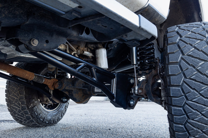 ReadyLIFT Tubular Radius Arm Kit on a vehicle: black tubular radius arm installed under a Super Duty front axle beside a large tire