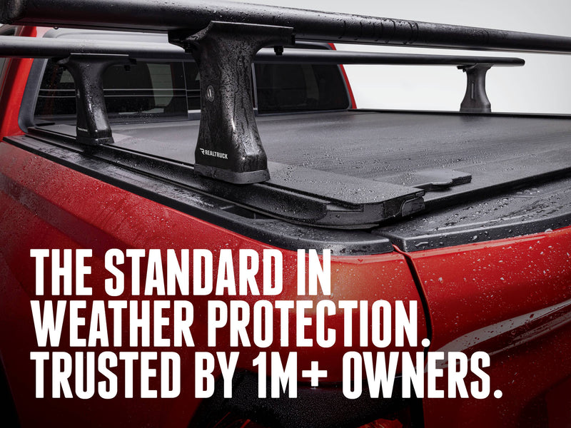 RetraxONE XR cover closed under a crossbar rack, beaded with rain, on a red pickup; overlay headline about weather protection (rack sold separately)
