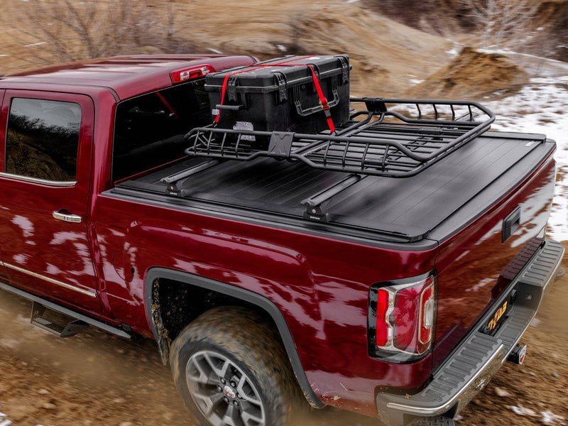 Outdoor shot of a red pickup on a dirt trail with the closed cover carrying crossbars and a loaded cargo basket (rack sold separately)