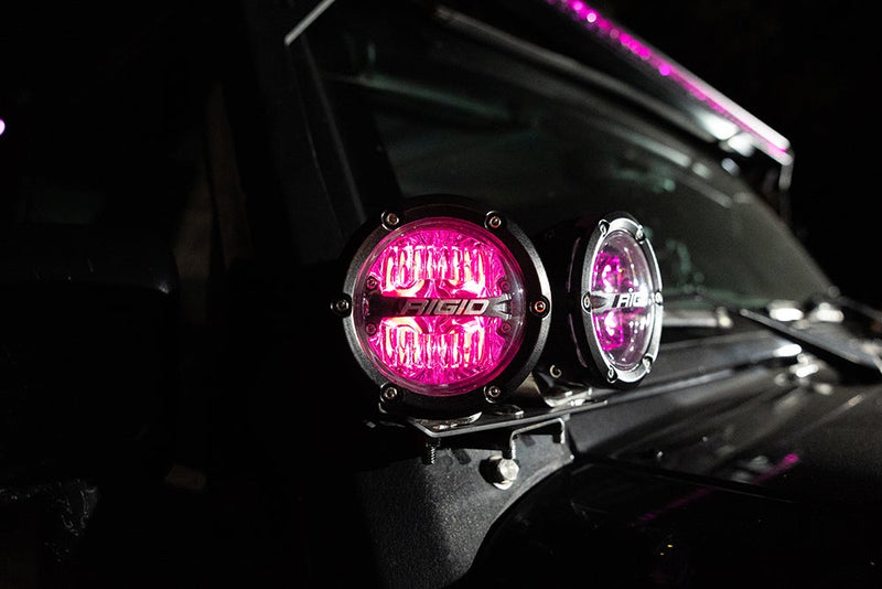 Rigid 360-Series PRO 4" Pair installed on a vehicle: two round Rigid 360-Series lights glowing pink on a cowl mount beside a windshield at night