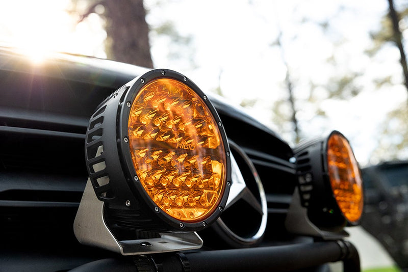 Rigid 360-Series PRO 9" installed on a vehicle: A large amber round LED light sits on the front of a dark vehicle with a second one beside it