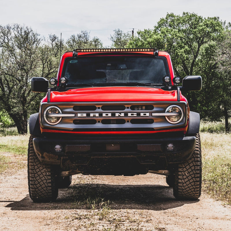 Rigid Standard Bumper 360-Series Fog Light Kit installed on a Ford Bronco: front view of a red Ford Bronco with BRONCO grille lettering and round fog lights in the bumper