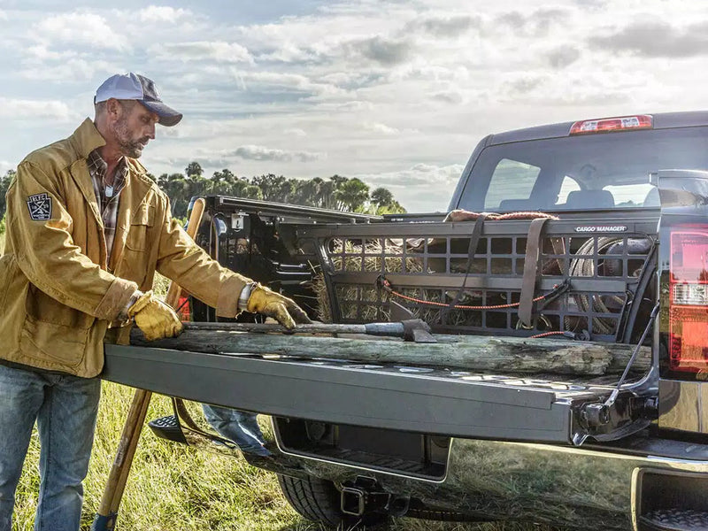 Roll-N-Lock Cargo Manager man unloading a fence post, bed divider holding gear behind (tonneau cover sold separately)