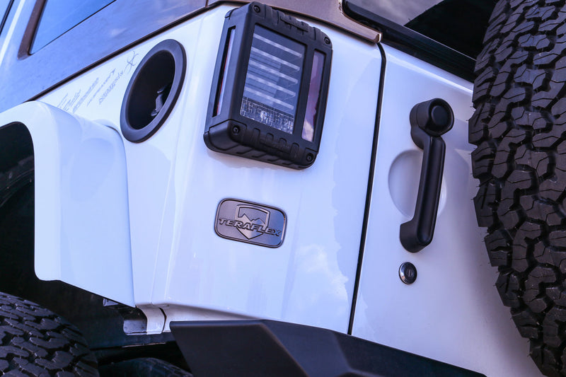 Close-up of the TeraFlex license plate delete badge on a white Jeep Wrangler JK tailgate