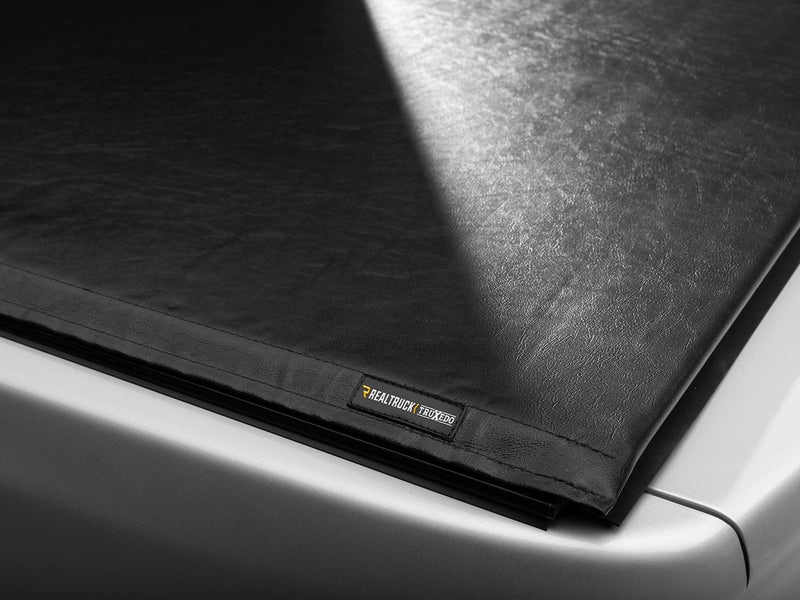 Close-up of the closed Lo Pro soft roll-up cover at the rear corner of the bed, showing the flat black vinyl top and the TruXedo label