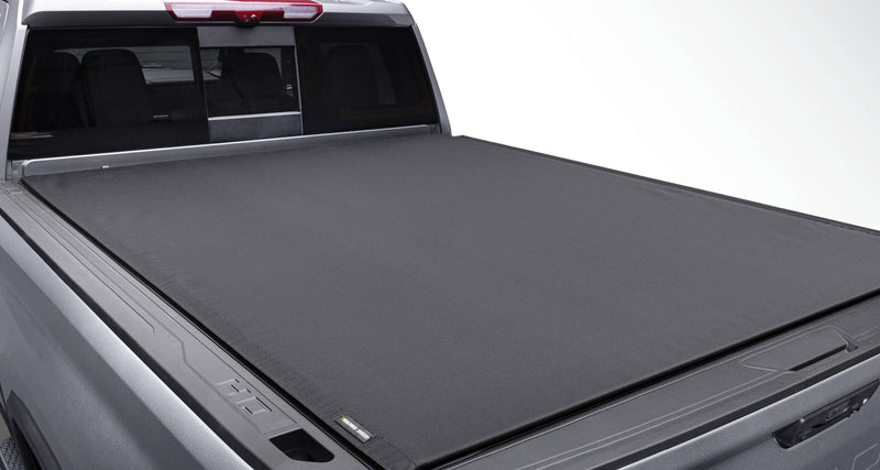 Black soft roll-up tonneau cover closed flat over a silver pickup bed, viewed from the rear corner