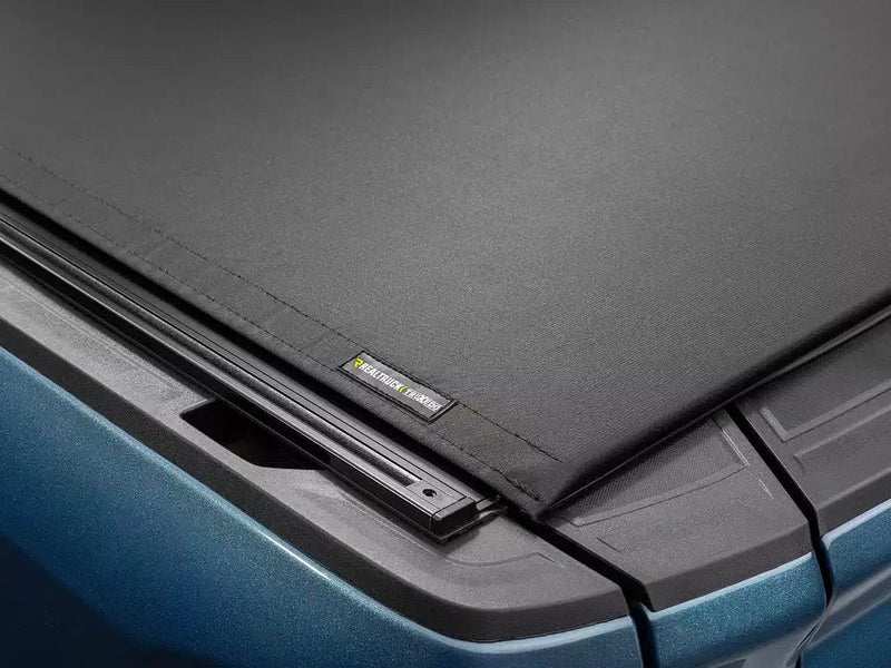Close-up of the closed black canvas at the rear corner, over the low-profile side rail with its T-slot channel and a small TruXedo label