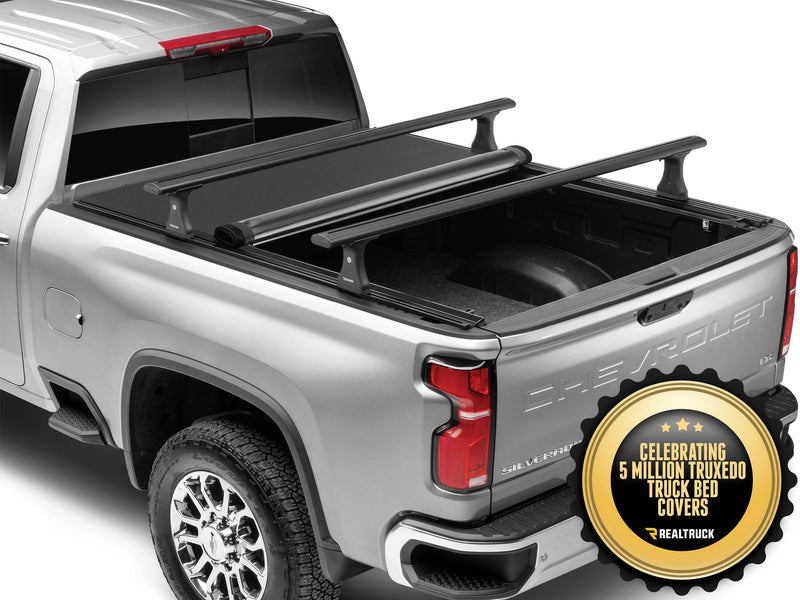Pro X15 TS partly rolled toward the cab on a silver pickup, with a seal reading Celebrating 5 million TruXedo truck bed covers; the roof-style crossbars are an accessory sold separately