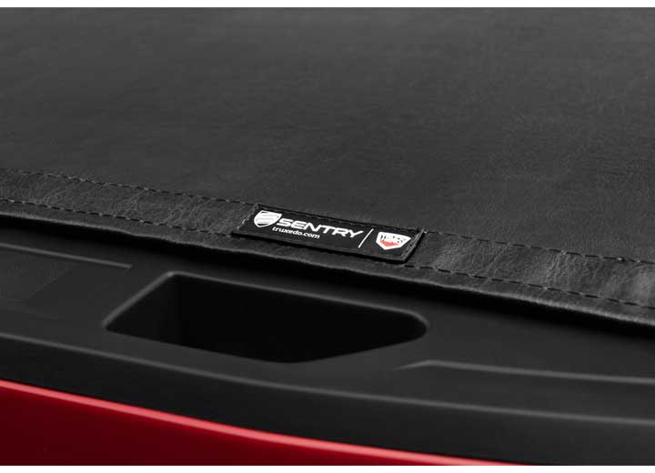Close-up of the SENTRY name plate beside the tailgate handle recess on a TruXedo Sentry hard roll-up tonneau cover