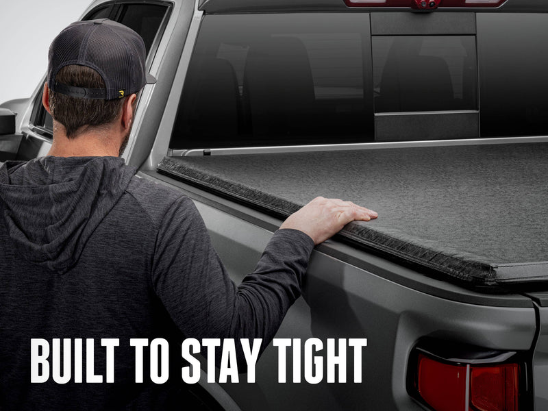 A man presses down on the taut TruXport vinyl top beside the bed rail, with the text Built to stay tight