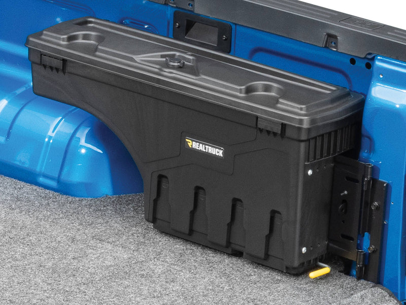 UnderCover SwingCase swing-out truck bed toolbox mounted over the wheel arch inside a blue pickup bed, lid closed