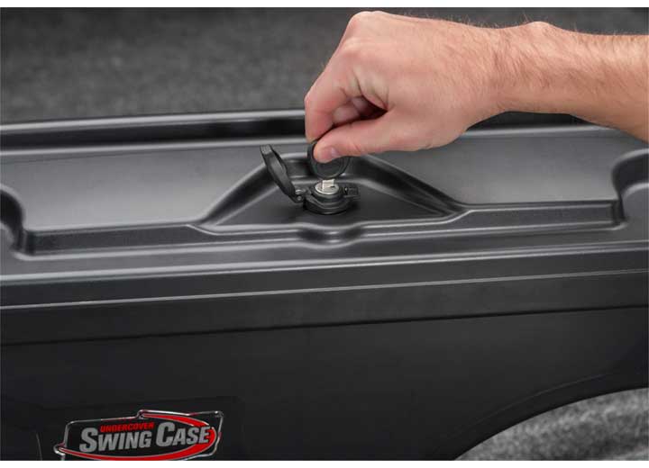 A hand turning the rotary latch on the closed lid of the UnderCover SwingCase truck bed toolbox