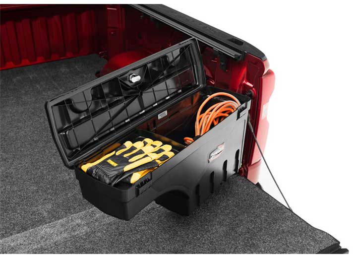 UnderCover SwingCase toolbox swung out over a lowered tailgate with the lid open, holding an orange extension cord and hand tools