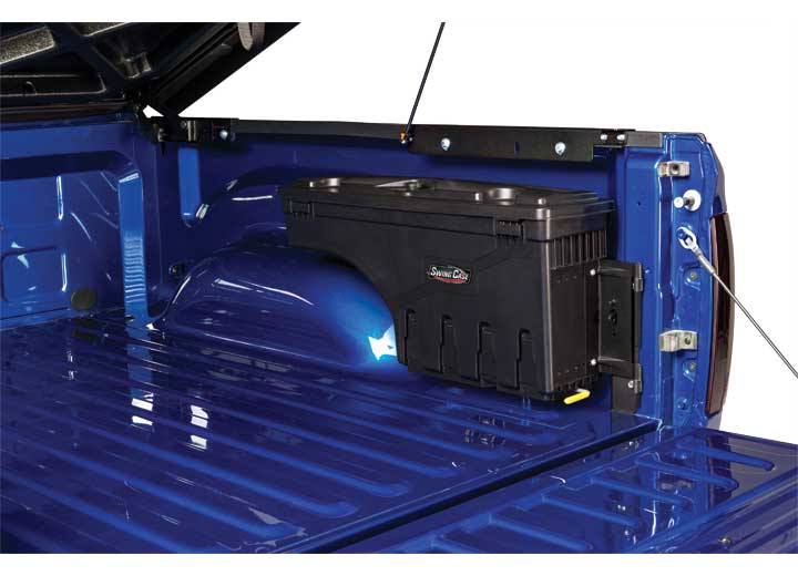 UnderCover SwingCase toolbox closed and sitting over the wheel arch of a blue pickup bed, striker bracket visible behind it