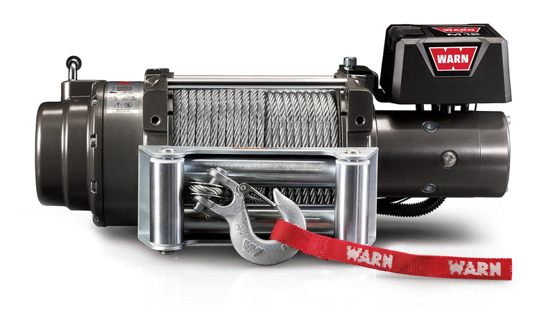 Warn M12 winch, front elevation on white, showing the large-frame body, steel wire rope on the drum, roller fairlead, clevis hook with red Warn strap and the control pack badged M12