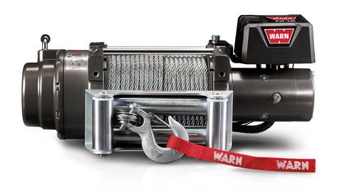 Warn M12 winch, front elevation on white, showing the large-frame body, steel wire rope on the drum, roller fairlead, clevis hook with red Warn strap and the control pack badged M12