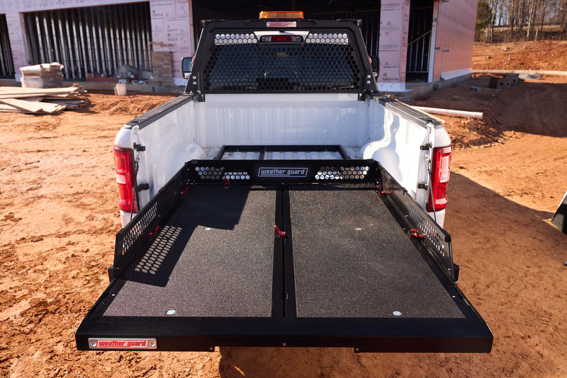 Weather Guard SB65-52-01 sliding truck bed fully extended over the tailgate of a white full-size pickup at a jobsite