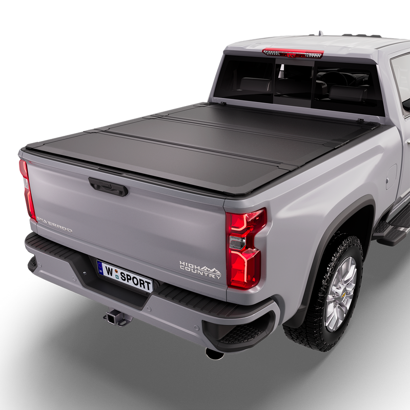 Worksport NEXUS hard folding tonneau cover on a pickup: studio render of a silver Chevrolet Silverado High Country from the rear quarter with a black NEXUS hard folding tonneau cover closed