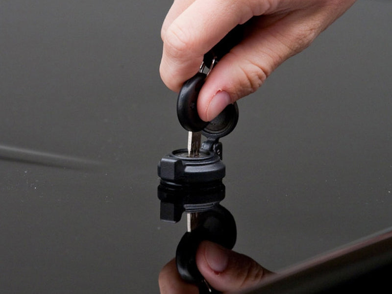 A hand turning a key in the center lock of the closed LUX lid.