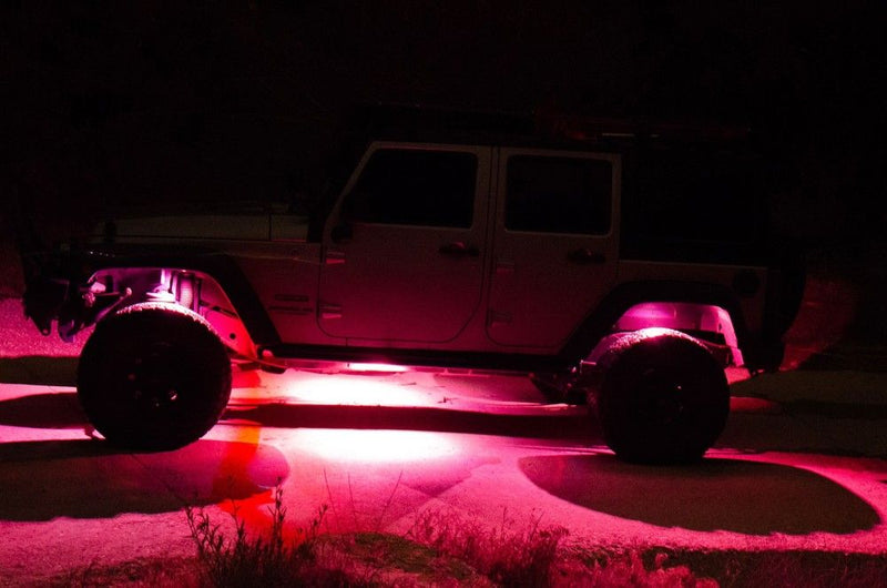 KC HiLiTES C-RGB Multi-Color Rock Light Kit, rock lights glowing pink under a Jeep at night