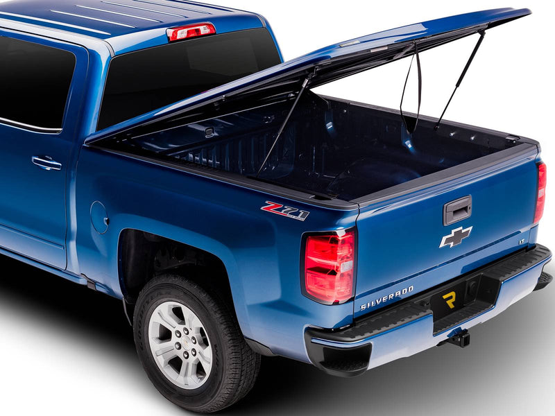 UnderCover LUX one-piece tonneau cover raised on its struts, rear three-quarter view, the underside of the lid and the empty bed floor both in frame.
