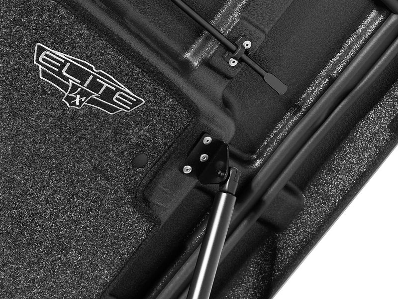 Close-up of the carpeted headliner with the prop rod and one gas strut crossing the frame.