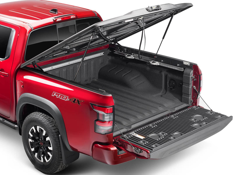 UnderCover Elite one-piece tonneau cover raised on its struts with the tailgate down, rear three-quarter view, the bed floor and the tailgate inner panel both open to the camera.