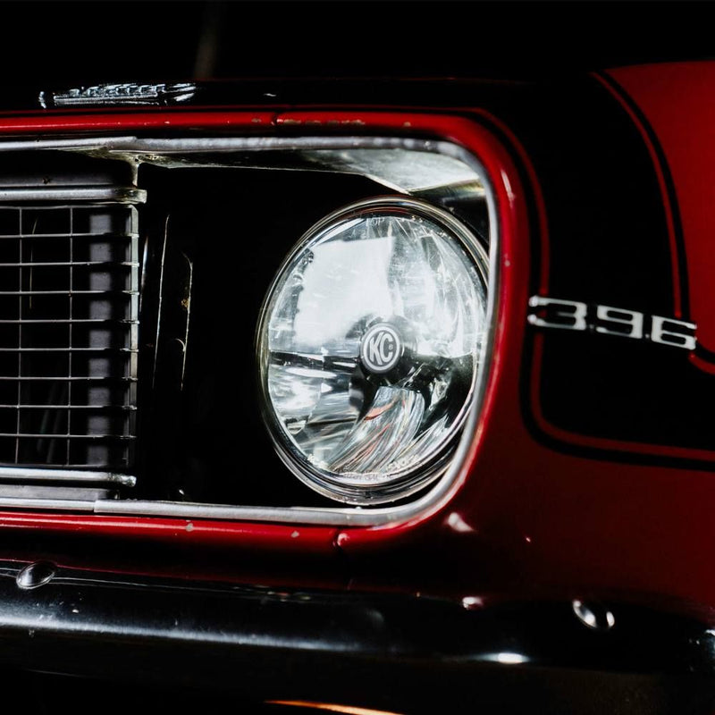 KC HiLiTES 7" Gravity LED DOT Headlight (H4 plug), close-up of a KC 7 inch Gravity LED DOT headlight in a red classic car