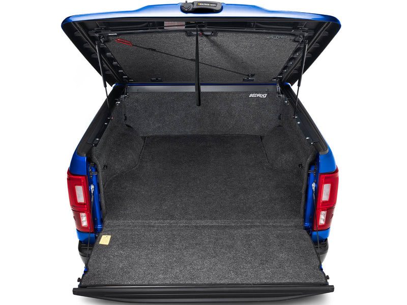 UnderCover Elite LX one-piece tonneau cover raised with the tailgate down, straight rear view over the dropped tailgate into the open bed.
