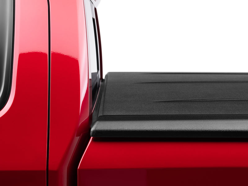 Macro of the closed SE lid's front corner, the textured edge molding sitting flush where the lid meets the cab end of the bed rail.