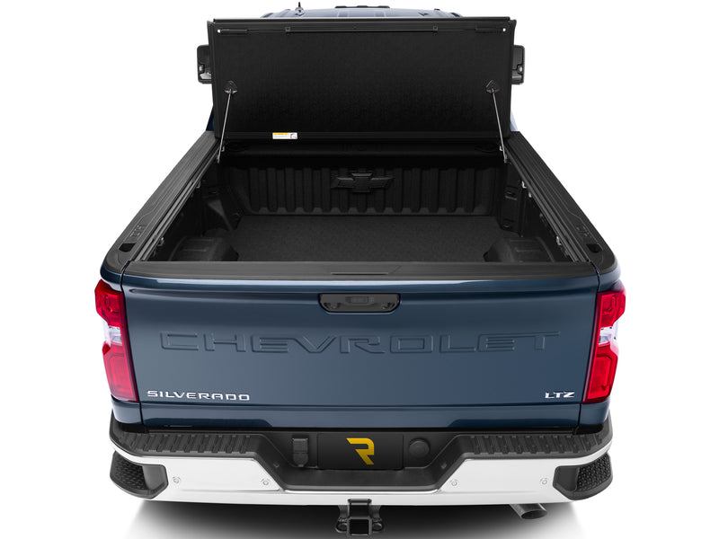 UnderCover Flex hard folding tonneau cover fully open and folded upright against the bulkhead with the tailgate closed, straight rear view into the empty bed.