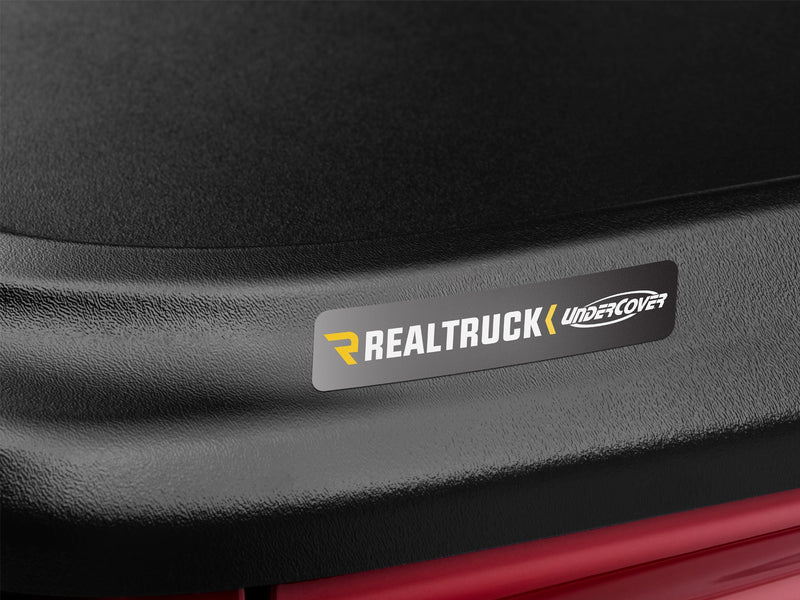 Close-up of the grey RealTruck UnderCover nameplate applied to the black textured rear lip of the SE lid.