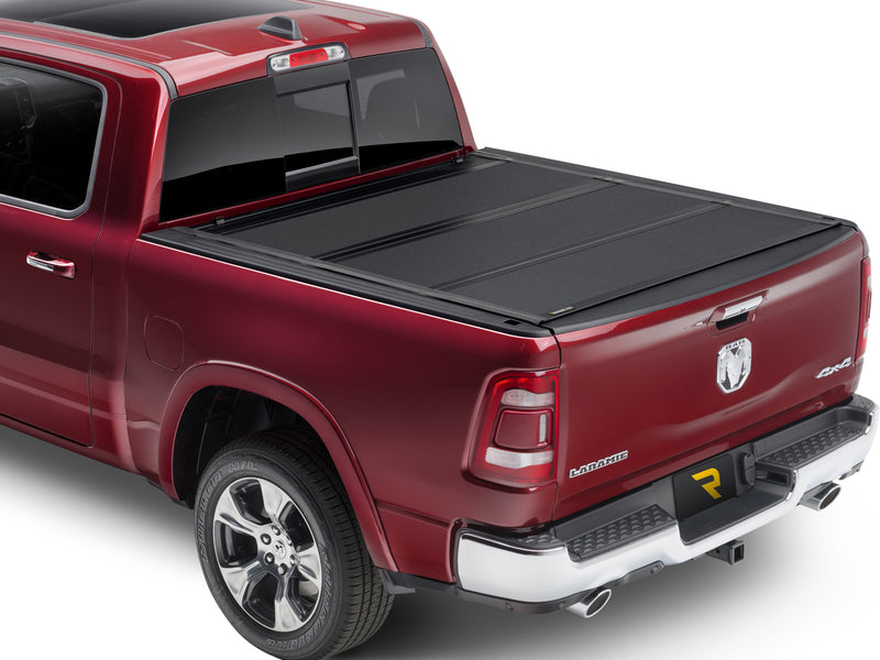 UnderCover ArmorFlex hard folding tonneau cover closed on a pickup bed, rear three-quarter view, textured matte-black aluminum panels sitting flush with the bed rails.