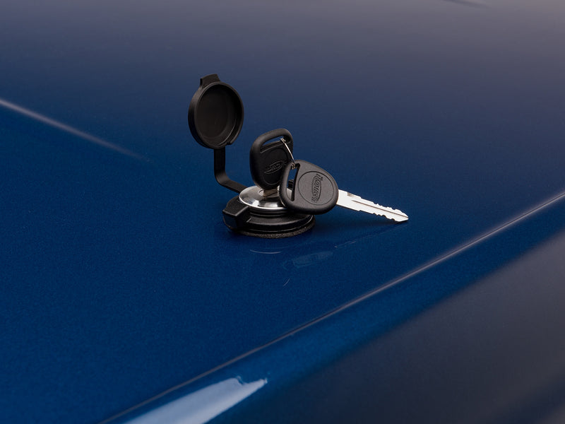 Close-up of the LUX lock cylinder with its weather cap flipped open, and the two supplied keys resting on the lid beside it.