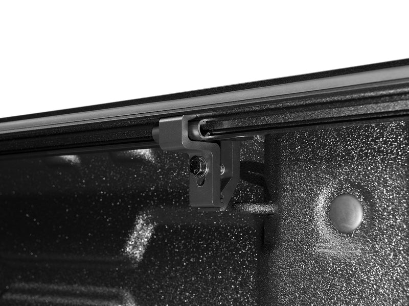 Close-up of the ArmorFlex no-drill clamp gripping the bed rail from inside the bed, showing the clamp foot and fastener.