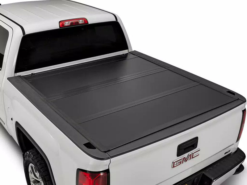 UnderCover Ultra Flex hard folding tonneau cover closed and flush on a pickup bed, rear three-quarter view showing the panel seams and low-profile rails.