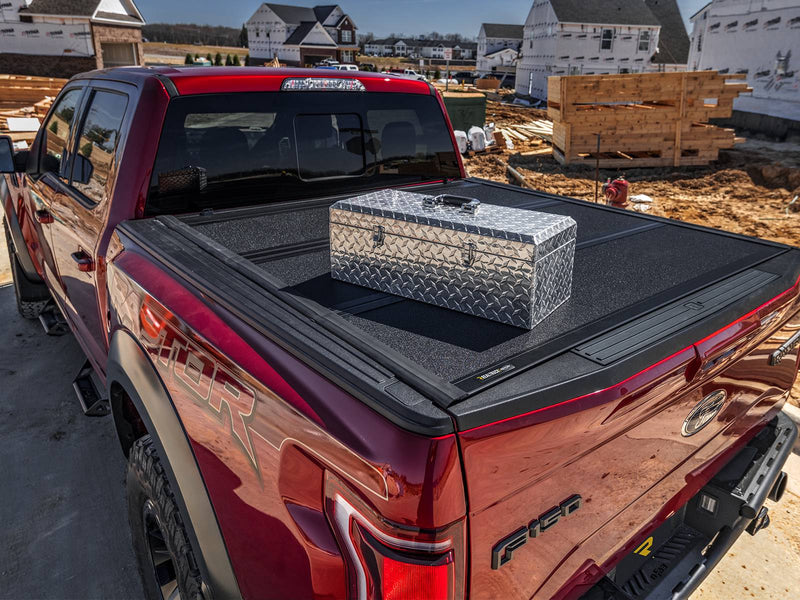 UnderCover ArmorFlex hard folding tonneau cover closed at a construction site with a tool chest resting on the panel surface, demonstrating the cover's load capacity.
