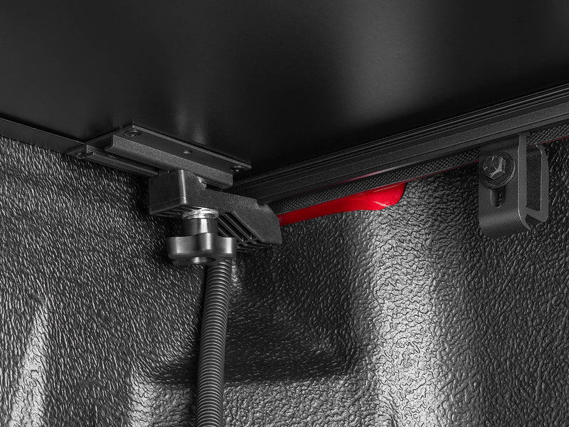 Close-up inside the bed of the Select rail clamp and the flexible drain tube running down the bed wall.