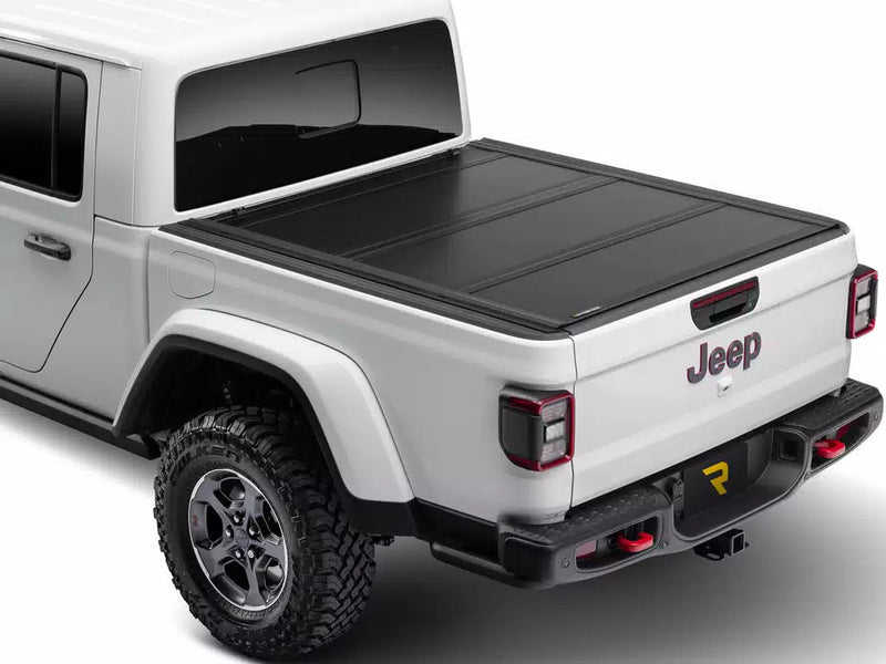 UnderCover Ultra Flex hard folding tonneau cover closed and flush on a pickup bed, rear three-quarter view, textured matte-black panels level with the bed rails.