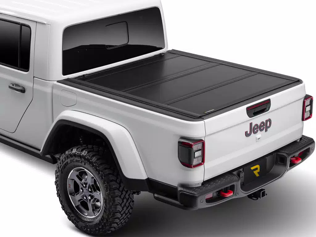 UnderCover Ultra Flex hard folding tonneau cover closed and flush on a pickup bed, rear three-quarter view, textured matte-black panels level with the bed rails.