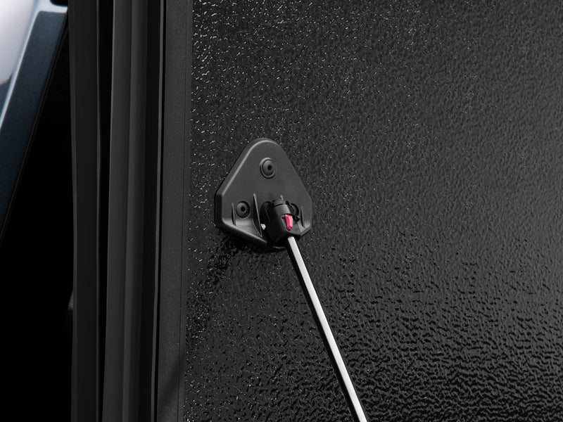 Close-up of the ArmorFlex prop-rod pivot bracket on the cover's textured Multi-Shield panel face with the rod extended.