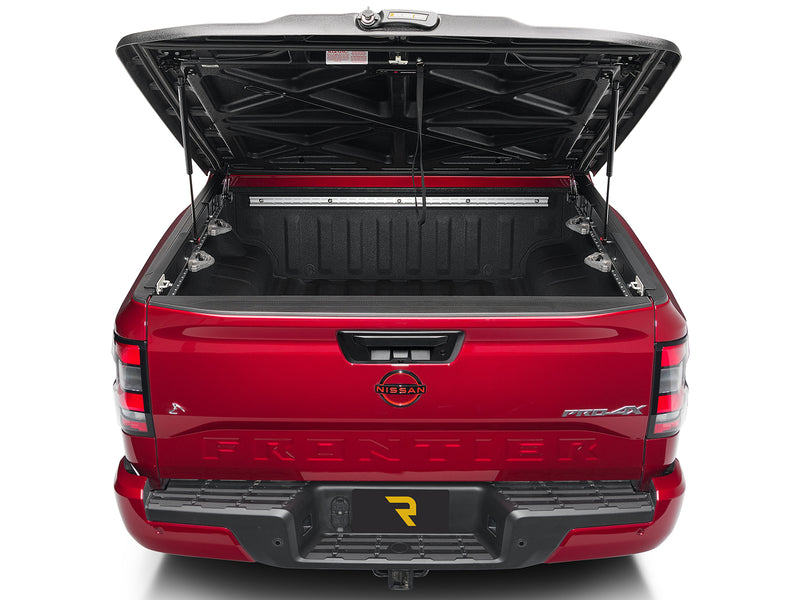 UnderCover Elite one-piece tonneau cover raised, straight rear view looking at the molded X-brace underside and the printed red warning decal.