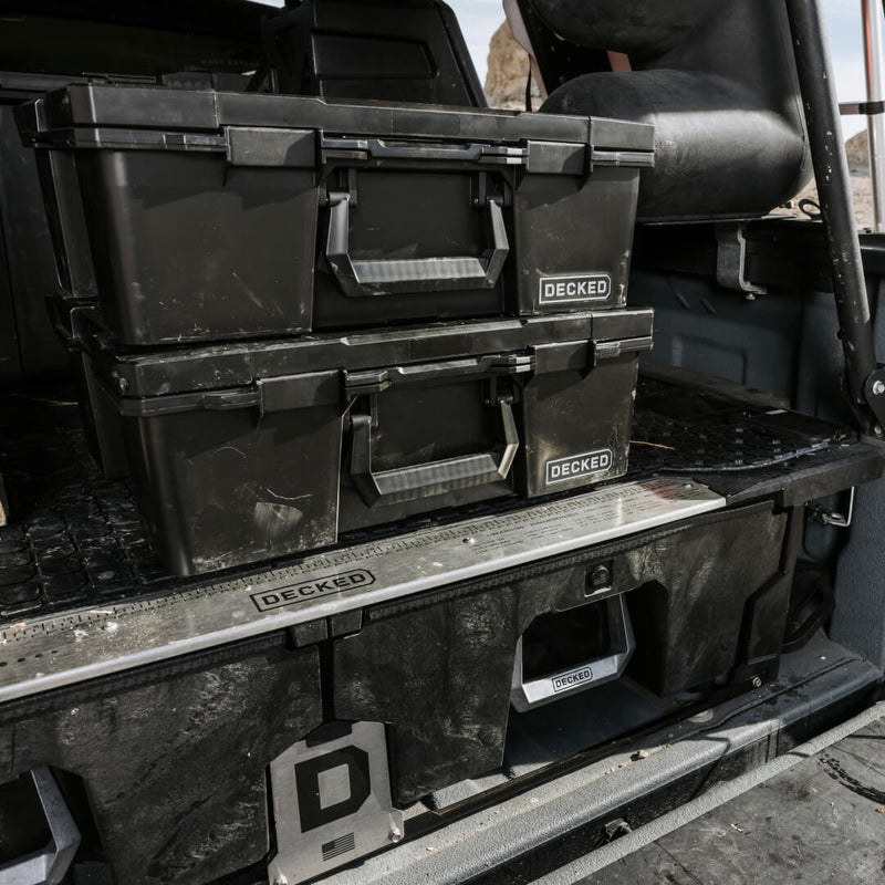Two Black DECKED Halfrack 32 cases stacked on a DECKED Drawer System in a dusty pickup bed